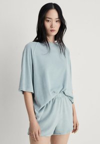 Lichtblauwe, zachte top met korte mouwen en een losse pasvorm, gecombineerd met bijpassende shorts met een elastische tailleband en een minimaal ontwerp.