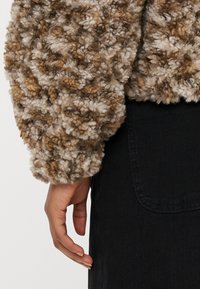 Bruine en beige pluizige trui met een getextureerd, pluizig oppervlak; losse pasvorm; voorzien van een brede manchetten en een casual ontwerp.