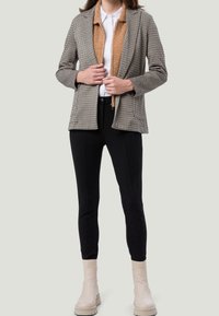 Marynarka w kratę z beżowym kołnierzem z sztucznego futra, zestawiona z dopasowanymi czarnymi spodniami i kremowymi botkami za kostkę. Gładka tekstura i dopasowany fason.