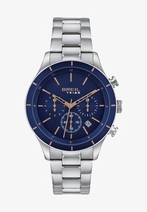 Herenhorloge met een roestvrijstalen band, een marineblauwe wijzerplaat, gouden accenten en drie sub-dials met datumnweergave op zes uur.