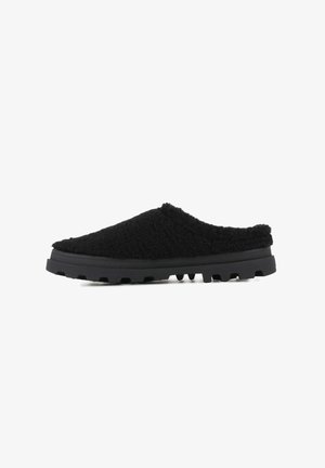 Scarpe slip-on nere con una tomaia testurizzata e pelosa e una suola in gomma spessa e resistente, dotata di motivi antiscivolo per una maggiore aderenza.