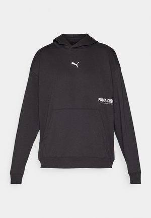 Črna kapuca Puma z sprednjim žepom, bel logotip na prsih in napis "PUMA CREW" natisnjen v beli barvi na strani. Mehka tkanina, običajen kroj.