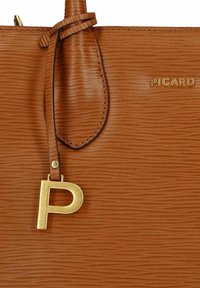 Borsa in pelle marrone con texture, charm a forma di lettera "P" dorata e logo "PICARD" dorato sulla parte anteriore.
