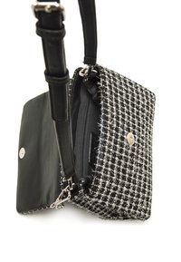 Schwarze und weiße Tweed-Tasche mit strukturiertem Gewebe und metallischen Akzenten, ausgestattet mit einem Frontklappenverschluss, einer Reißverschlusstasche und einem verstellbaren Ledertrageriemen.