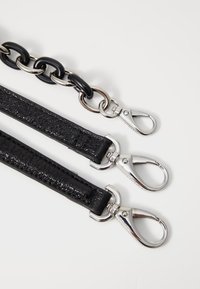 Cintura in pelle nera con una finitura testurizzata, accompagnata da una grande catena metallica nera e argento, dotata di ganci a pressione argentati.