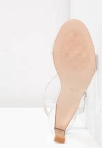 Sandale blanche à talon haut vue de côté de la semelle, semelle beige avec motif antidérapant, talon carré, taille 37, fabriquée en Espagne.