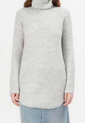 Femme portant un pull à col roulé côtelé gris clair à manches longues et une jupe en denim bleu clair, vue des épaules aux hanches.