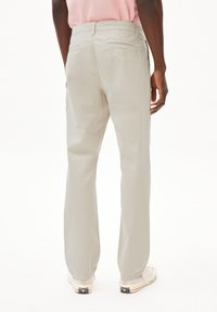 Lichtgrijze broek met een rechte pijp, met achterzakken en een gladde stofstructuur. G gedragen met casual schoeisel.
