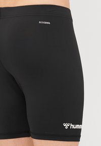 Črne kopalne hlače imajo oprijet kroj, izdelane so iz gladkega materiala. Znamke "BECOOL" in "hummel" so natisnjene v beli barvi.