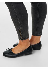 Musta nahkasandaalit, joissa on pyöreä varvas, nauhakoriste ja matala korko. Yhdistetty tummiin slim-fit farkkuihin, joissa on vetoketjuhihat.