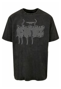 Svart denim t-skjorte med stor hvit grafisk tekst på forsiden, korte ermer og en avslappet passform. Steinvasket tekstur er synlig.