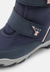 Botte étanche bleu marine avec une texture lisse, deux sangles Velcro, semelle en caoutchouc grise, et un logo accent rose avec des étoiles.