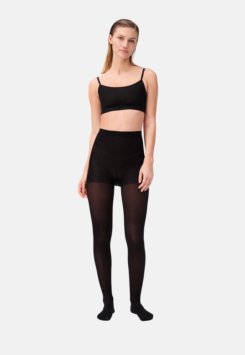 Zwarte naadloze bralette met verstelbare banden, gecombineerd met hoge zwarte tights, beide in een soepele, rekbare stof.