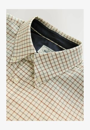 Camicia a quadretti beige con linee marroni e grigie, con colletto classico e bottoni chiari, posata su uno sfondo neutro.