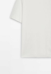 T-shirt beige clair à manches courtes en coton doux. Il présente une coupe décontractée, un col rond et ne comporte aucun motif ni accent visible.