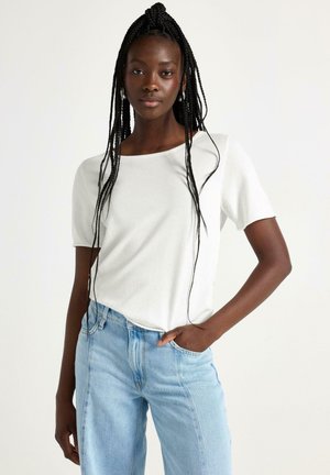 Hvid kortærmet t-shirt lavet af blødt stof, rund halsudskæring, med en afslappet pasform. Sammen med lyseblå højtaljede jeans.