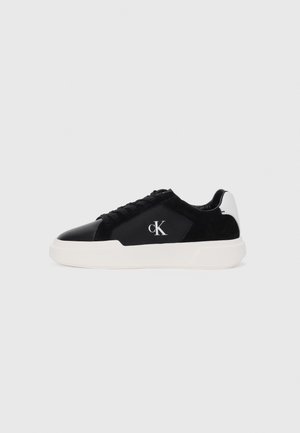 Sneakers in bianco e nero con punta in pelle verniciata, dettagli in suede e suola in gomma. Logo ricamato sul lato. Design a collo basso.
