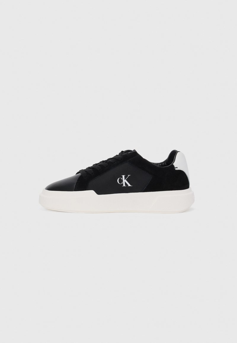 Tenis negri și albi, cu vârful din piele lacuită, accente din suede și talpă din cauciuc. Logo brodat pe lateral. Design de tip low-top.