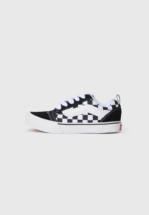 Tenisi din pânză alb-negru, cu un model în carouri, șireturi albe, guler captusit și talpă de cauciuc albă. Detaliu proeminent cu logo-ul Vans pe călcâi.