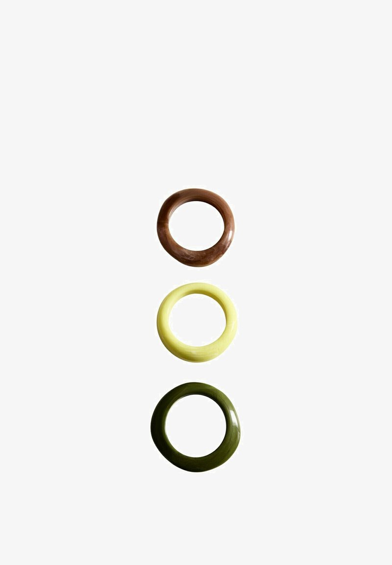 Trois anneaux circulaires lisses en marron, jaune pâle et vert foncé, disposés verticalement sur un fond blanc.