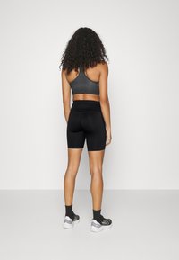 Shorts deportivos negros y un sujetador deportivo gris, diseño ajustado, textura suave, estilo de espalda nadadora, combinados con calcetines negros y zapatillas.