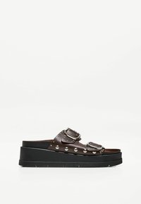 Sandales à plateforme marron avec deux boucles réglables, accents cloutés, semelle noire robuste, et dessus en cuir avec une finition texturée.