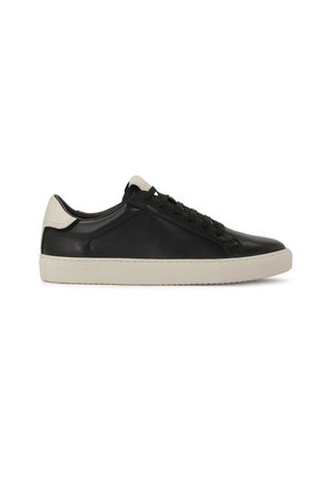 Zapatilla de deporte negra de cuero con suela de goma blanca, que presenta una textura suave, cordones planos y una tapa del talón en contraste de color blanco roto.