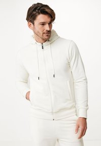 Vit zip-up hoodie i mjukt tyg, med justerbar huva, framfickor och kontrasterande svart dragkedja.
