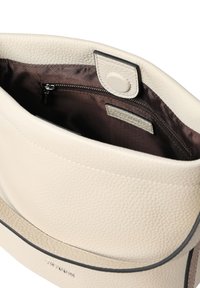 Kremfarvet læderhåndtaske med pebble-lignende struktur, magnetisk lukning og mørkebrun stofindvendig med lynlåslomme.