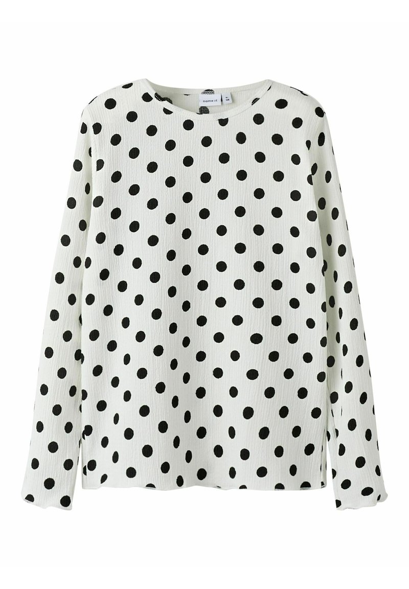Langermige shirt in het wit met zwarte stippen. Ronde hals, gestructureerde stof en zijsplitten voor gemak in beweging.