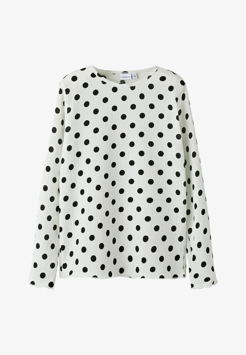 Langermige shirt in het wit met zwarte stippen. Ronde hals, gestructureerde stof en zijsplitten voor gemak in beweging.