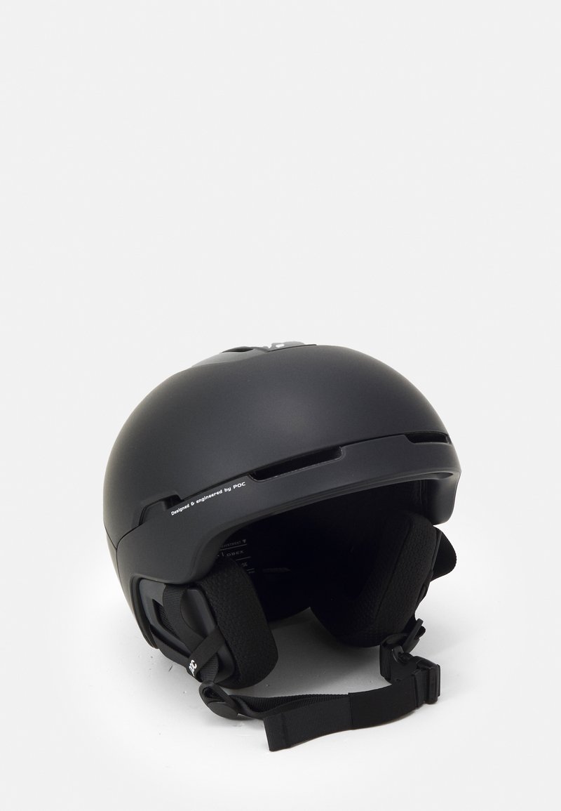 Black ski helmet with a smooth matte finish, ventilation slots, cushioned interior, adjustable chin strap, and branding on the side.