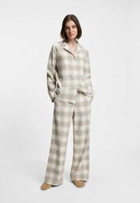 Plaid two-piece set in beige and light blue tones, featuring a button-up shirt with a collar and wide-leg pants; soft texture.