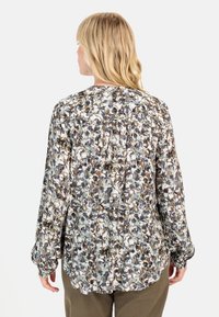 Langærmet bluse i letvægtsstof med blomstermønster i brun, grøn og creme, med rynkedetaljer bagpå.