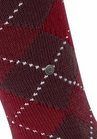 Calze lavorate a maglia con un motivo argyle marrone scuro e bordeaux con accenti bianchi, e un piccolo bottone logo in metallo sul lato.