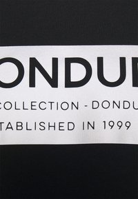 Tissu noir avec un rectangle blanc affichant un texte noir en gras : « DONDUP COLLECTION - DONDUP ESTABLISHED IN 1999. »