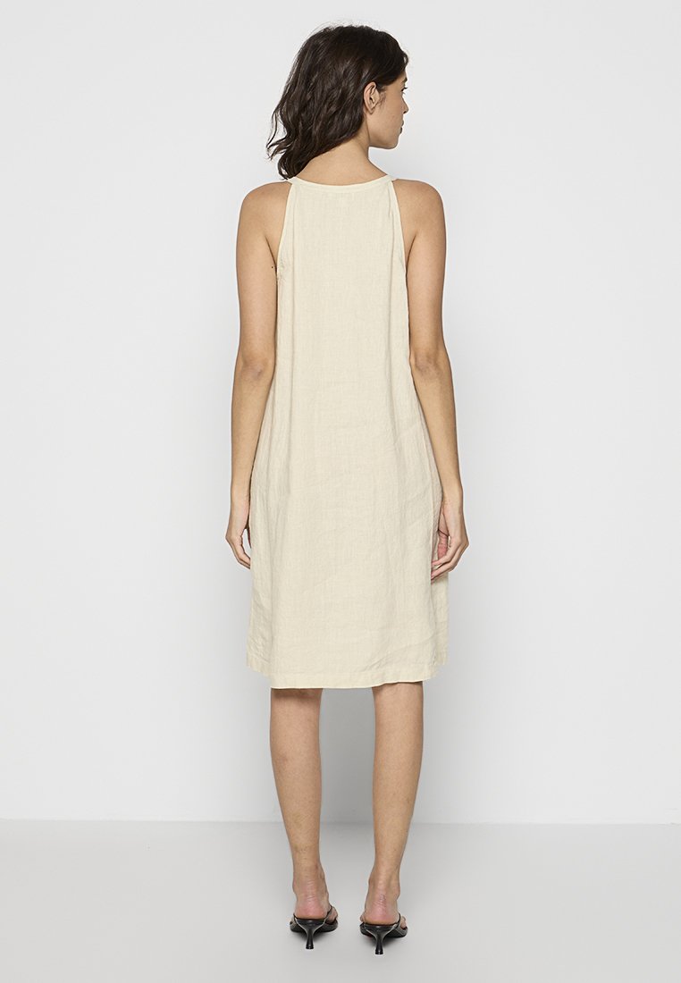 Beige Leinen-Kleid ohne Ärmel mit lockerer Passform, knielang, mit einem einfachen Rückendesign und seitlichen Schlitzen für eine angenehme Bewegungsfreiheit.