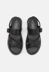 Czarne sandały z krzyżującymi się paskami i regulowanym zapięciem. Wykonane z gładkiego materiału z teksturowaną podeszwą, rozmiar 31.