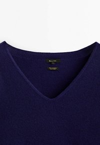 Pull en cachemire navy avec un design en V, un col côtelé et une texture douce. Étiquette indiquant 100 % cachemire, fabriqué en Chine.