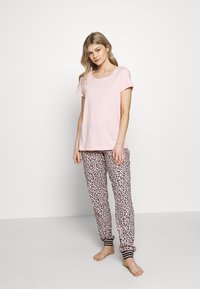 Lichtroze katoenen T-shirt met korte mouwen gecombineerd met joggingsbroek in luipaardprint met zwarte enkelboorden en een zachte textuur.