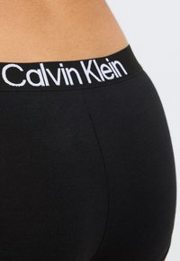 Μαύρα βαμβακερά μποξέρ με φαρδιά μαύρη ζώνη και λευκό λογότυπο "Calvin Klein", ομαλή υφή και εφαρμοστή σχεδίαση.