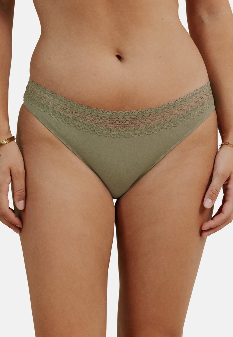 Bas de bikini vert olive avec une taille en dentelle festonnée. Matériau doux avec une couverture modérée, présentant une texture lisse et un design simple.