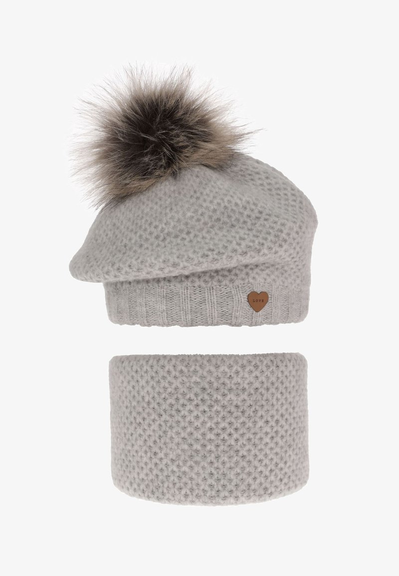 Cappello grigio lavorato a maglia con un pompon soffice e un piccolo dettaglio a cuore. Accompagnato da una scaldacollo grigia coordinata con una texture simile.