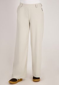 Crème-kleurige wijde broekspijpen van een soepele stof, met zijzakken en een platte tailleband. Opvallend door de losse pasvorm.