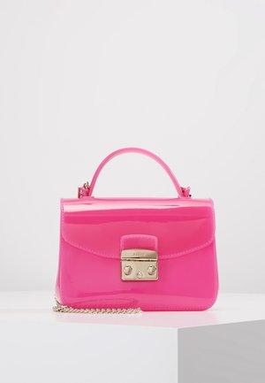 Błyszcząca torebka w intensywnym różowym kolorze z górnym uchwytem, złotym zamknięciem na zatrzask i srebrnym paskiem łańcuszkowym, leżąca na białej powierzchni.