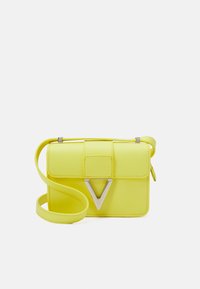 Geel leren crossbody tas met een klepsluiting, voorzien van een zilveren V-vormige accent en een verstelbare schouderriem. Gladde textuur en een compact ontwerp.