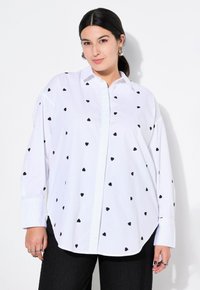 Witte overhemd met zwarte hartprint, met een ontspannen pasvorm en lange mouwen. Fijne stof en klassiek kraagontwerp.