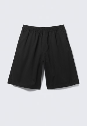 Zwarte loszittende korte broek met elastische tailleband en zijzakken, weergegeven op een lichtgrijze achtergrond.