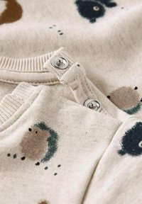 Kokvilnas krekls ar beigu audumu, ar dzīvnieku rakstiem brūnā, melnā un zaļā krāsā. Iekļauts spiedpogu aizdare apkaklē un ribota apdare.