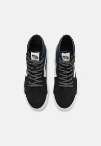 Hoge sneakers van suède en canvas. Zwart en marineblauw kleurenpalet, met grijze accenten en patroonveters. Rubberen zool.